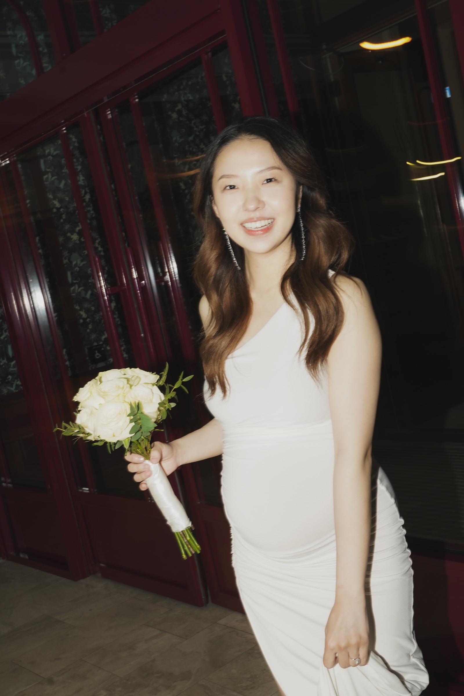 A smiling bride holding a white rose bouquet