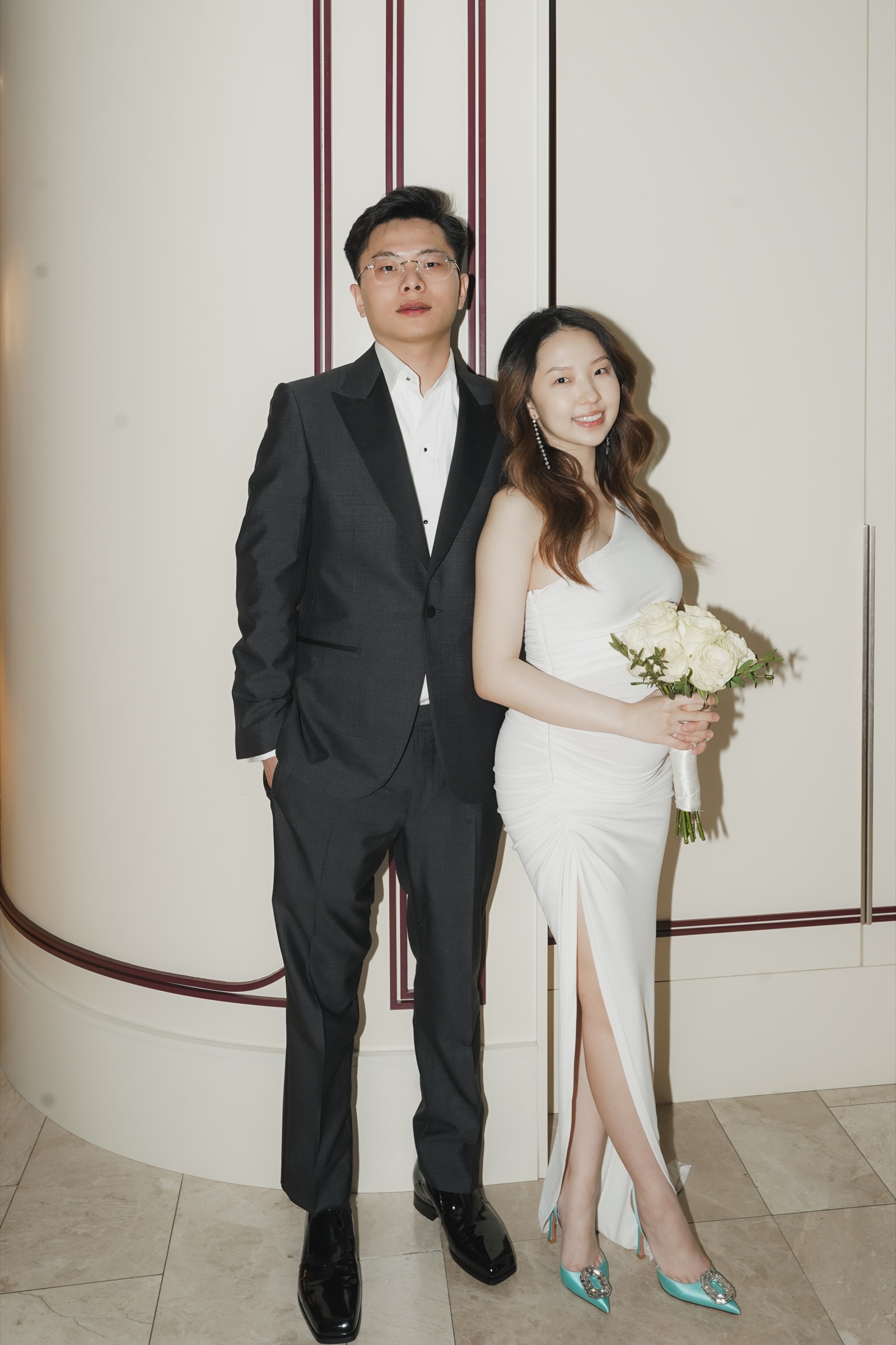 Newlyweds posing before an elegant cream and burgundy wall